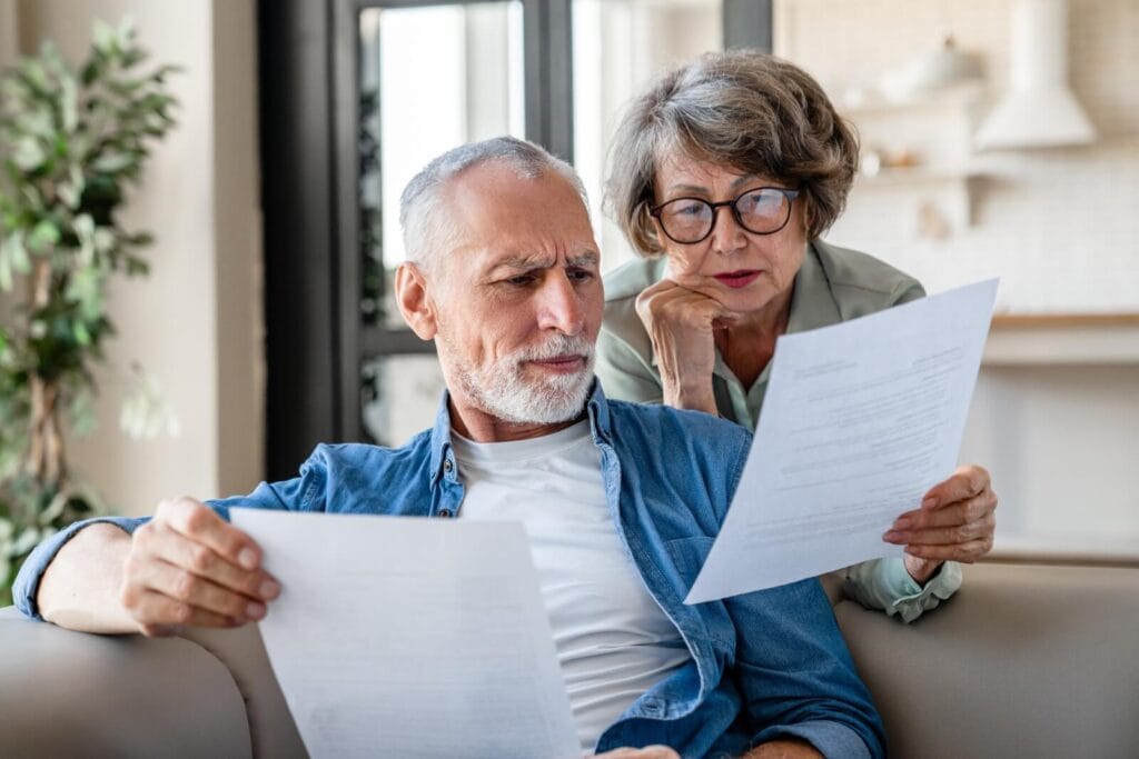 An older adult man and woman look over paperwork together.