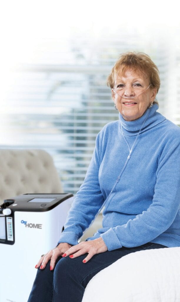 A seated woman is using the OxyHome device.