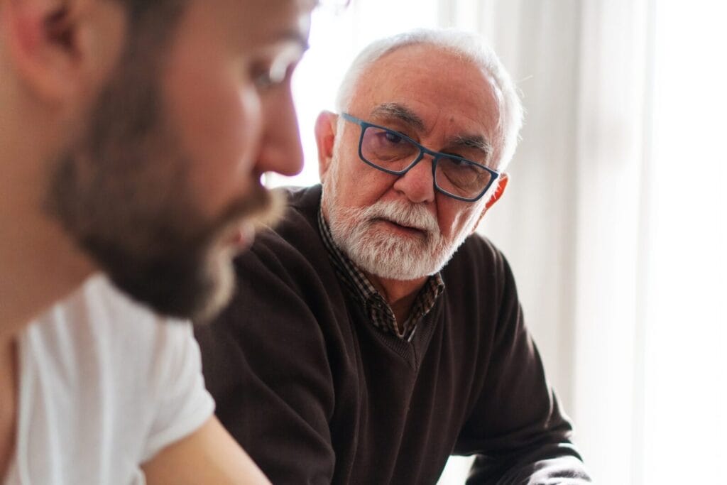 An older adult man is having a discussion with his son.
