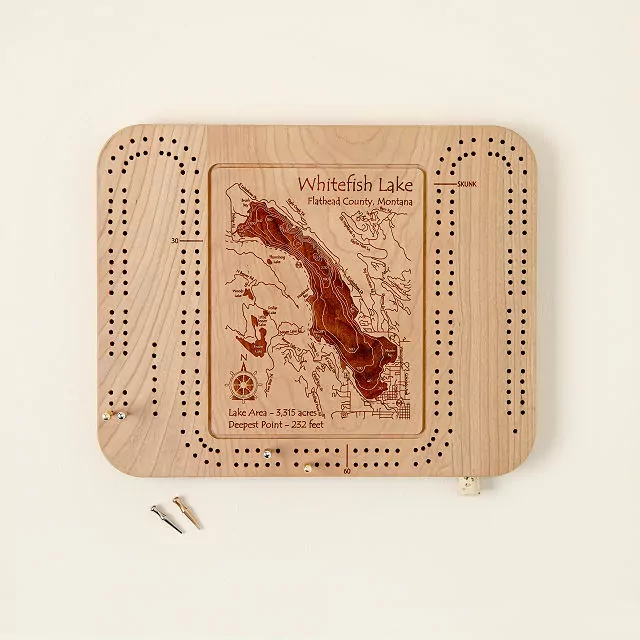 Product image of a wooden cribbage board with peg holes for scoring and a carved image of Whitefish Lake in Flathead County, Montana.
