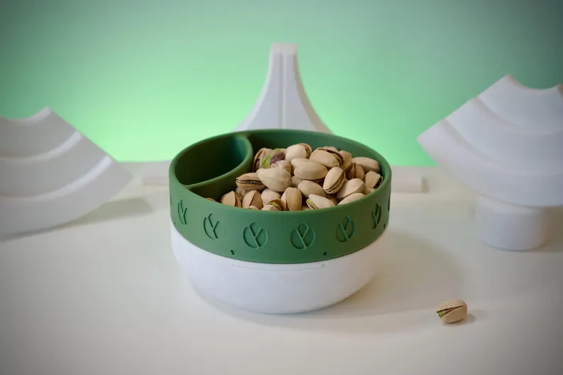 Product image of a bowl that has a slot for nut shells. The bowl holds pistachio nuts in their shells.