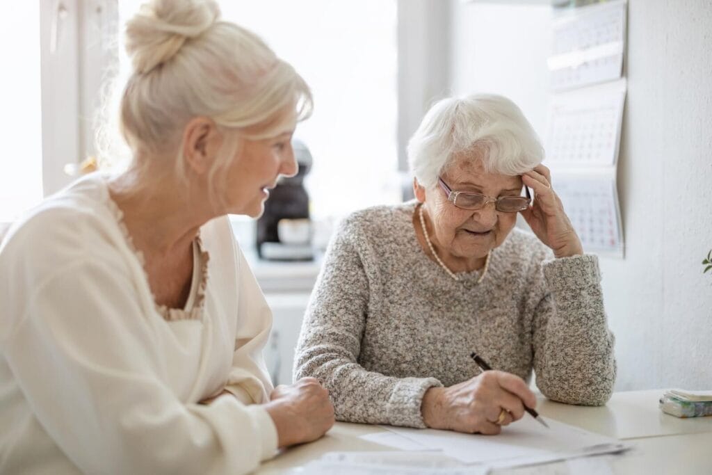 A woman helps her older adult mother with some paperwork.