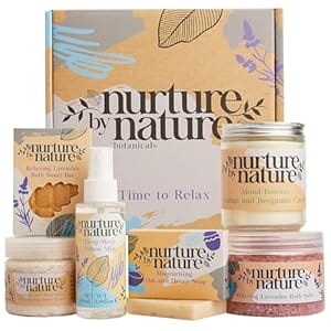Image of Nurture by Nature brand products, including a candle, a jar of bath salts, a bar of soap, pillow mist in a spray bottle, a jar of body scrub, and a bath bomb bar.