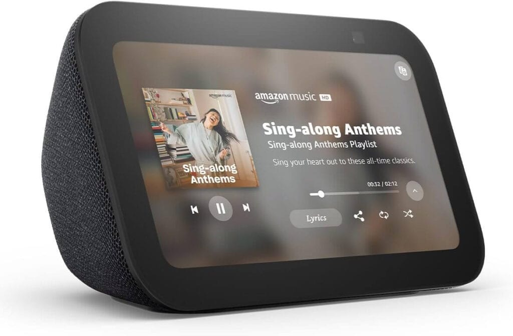 Image of the Amazon Echo Show. The black device's screen displays a graphic showing a song, album cover, and song title and artist.